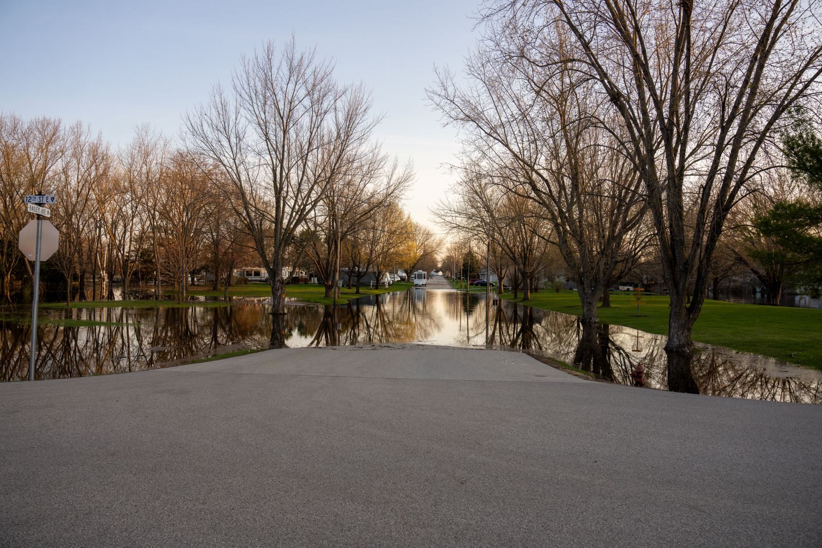 Peaceful spring scene of flooded park area in Wabasha, MN with bare trees reflecting in water.